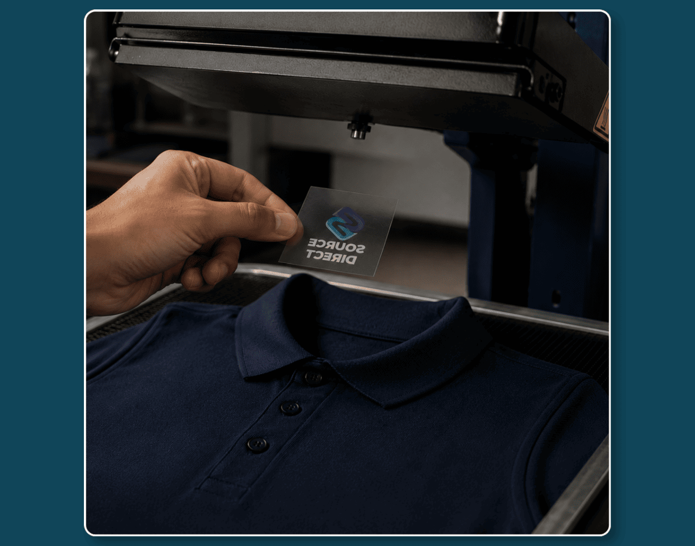 Heat transfer printing being applied to a navy polo shirt using a heat press.